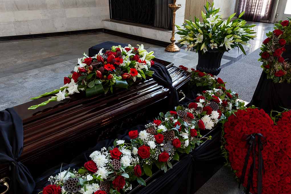 Closed casket with flower arrangements in funeral home.