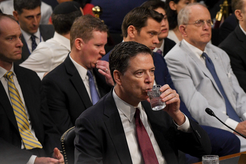 Man drinks water during a formal meeting or hearing.