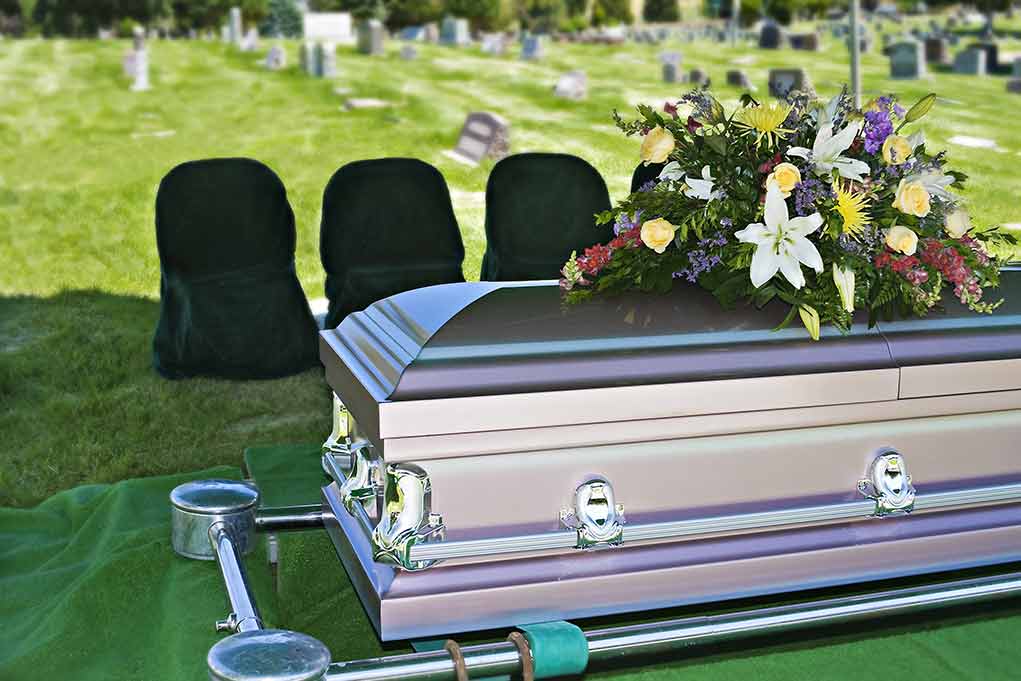 Casket adorned with flowers at outdoor funeral service.