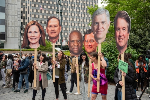 People holding large cutouts of U.S. Supreme Court justices.