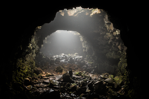 Sunlight entering a dark, rocky cave opening.