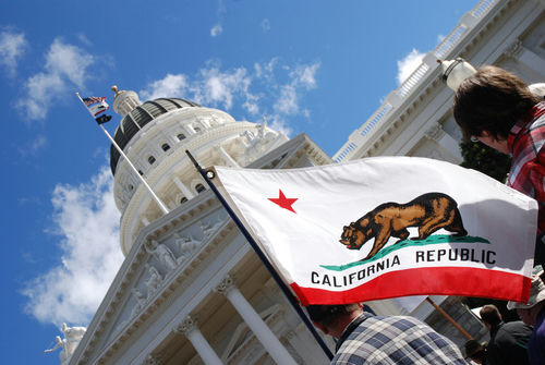 California state flag in front of Sacramento Capitol building.