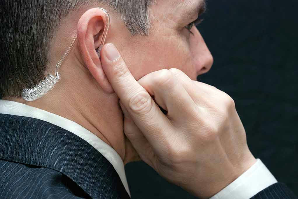 Man wearing earpiece adjusting it with finger.