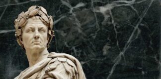 Marble statue of Julius Caesar with a serious expression against a dark background