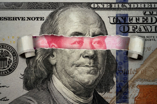 Torn dollar revealing Chinese yuan behind Benjamin Franklins eyes.