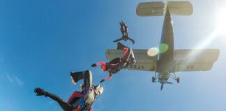 Skydivers freefalling below a small aircraft blue sky