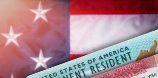 Green card and visa with U.S. flag background.