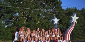 A group of young women on a decorated parade float celebrating a patriotic event