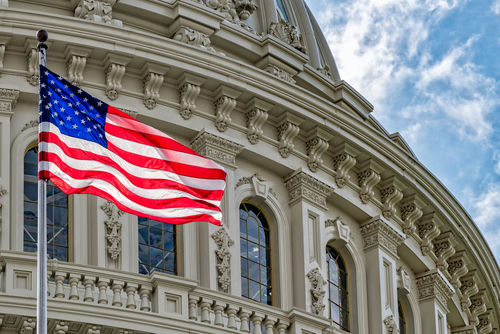 US flag waving in front of Capitol building.